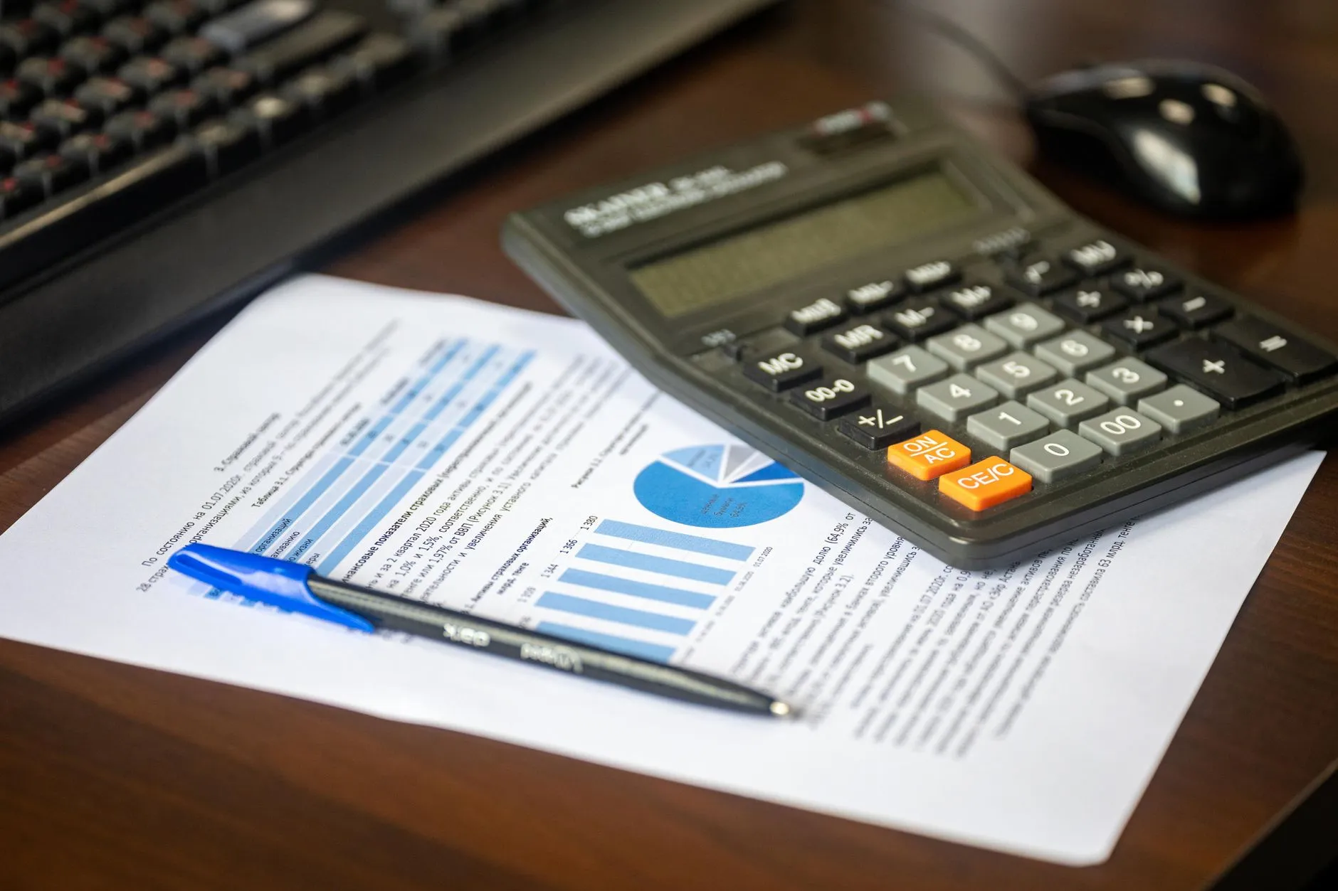 A calculator and pen on top of a printed financial report