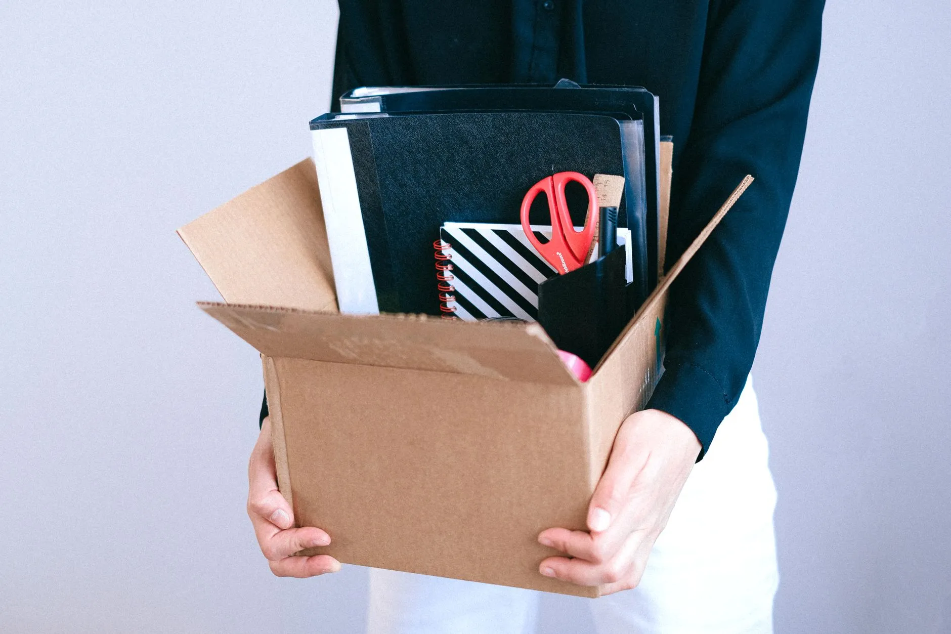 A person carrying a cardboard box of office belongings